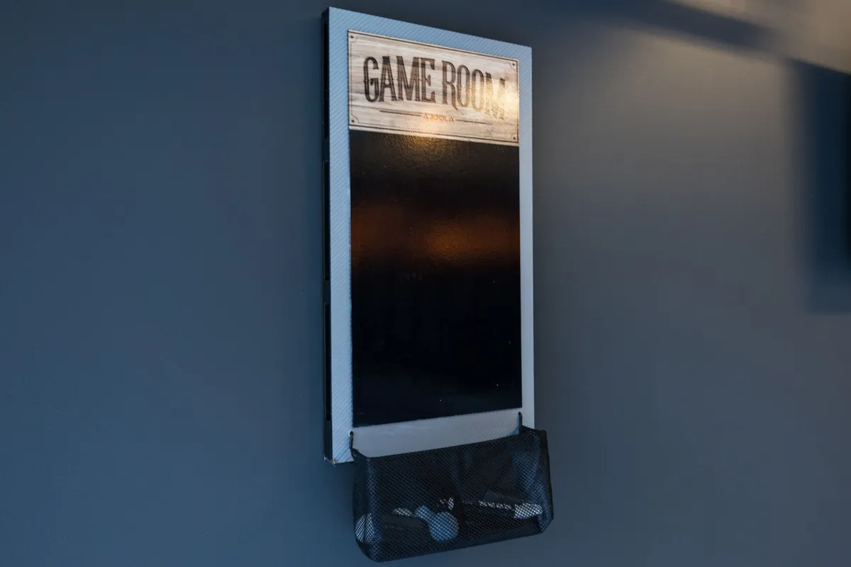 An inviting game room sign hangs above a mesh storage bag, hinting at a collection of games and playful activities within the space. The scene feels relaxed and ready for group gatherings.