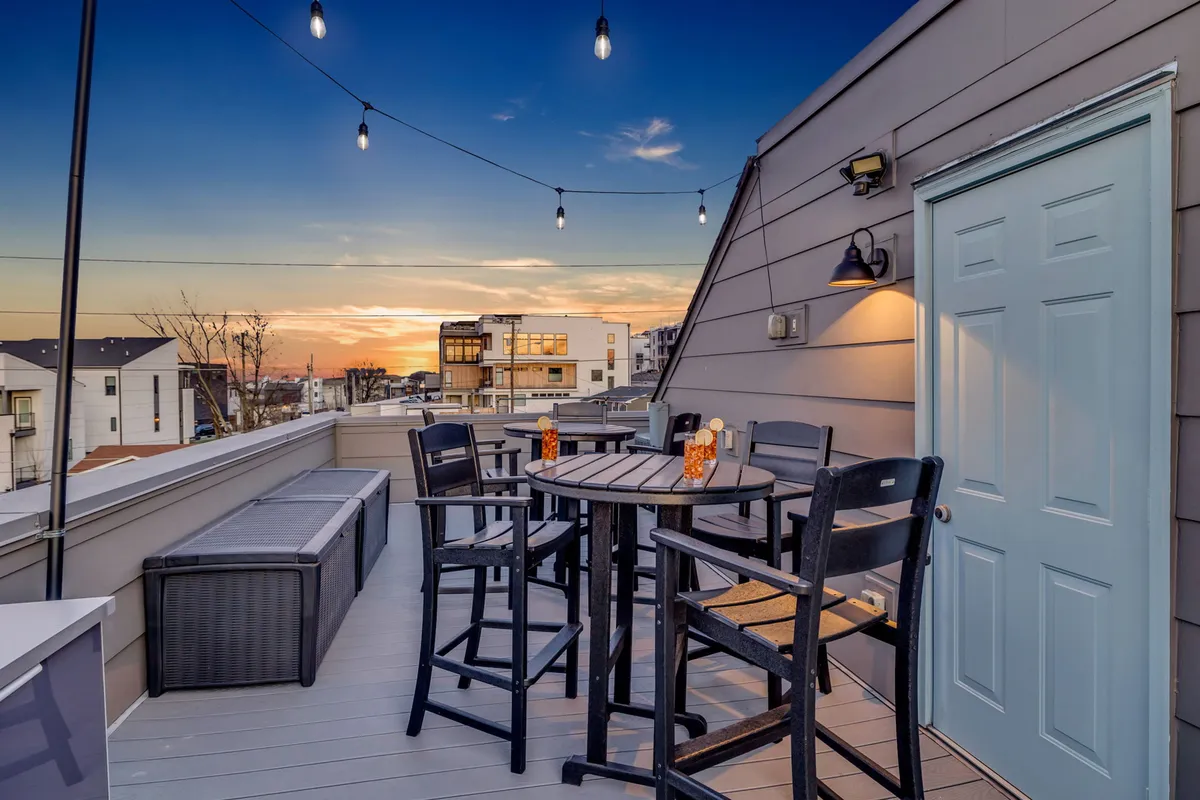 An inviting exterior seating area strung with lights set against a beautiful sunset. Cozy outdoor furniture suggests a place for families to gather, relax, and unwind after a day exploring Nashville’s top attractions.