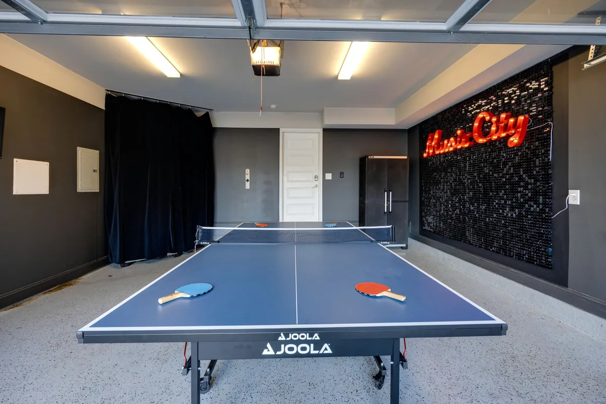 An action-focused image that centers on the ping pong table, with a neon sign and dark accent wall in the background. The setup highlights the game-centric nature of the space, suggesting both friendly competition and a cool hangout spot.