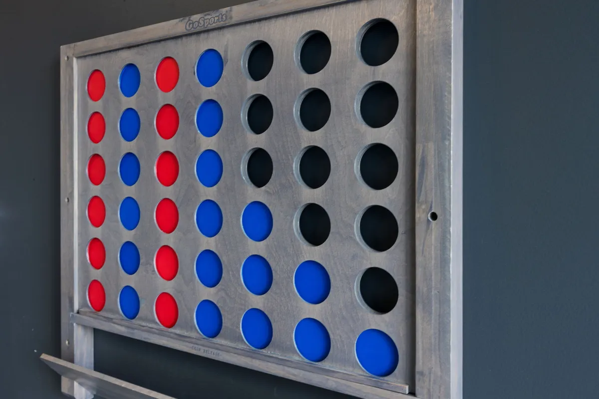 A close-up of a colorful Connect Four game board with red and blue tokens, emphasizing the variety of games available for group entertainment and friendly rivalry.