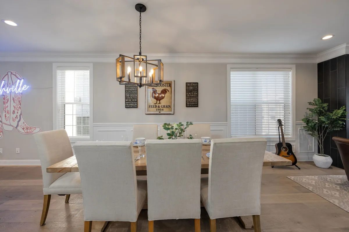 Here, the dining area is shown with a large table set beneath a chandelier, surrounded by decorative wall art, a guitar, and touches of greenery. The setup is perfect for group meals, celebrations, and intimate conversations, echoing Nashville's musical spirit.